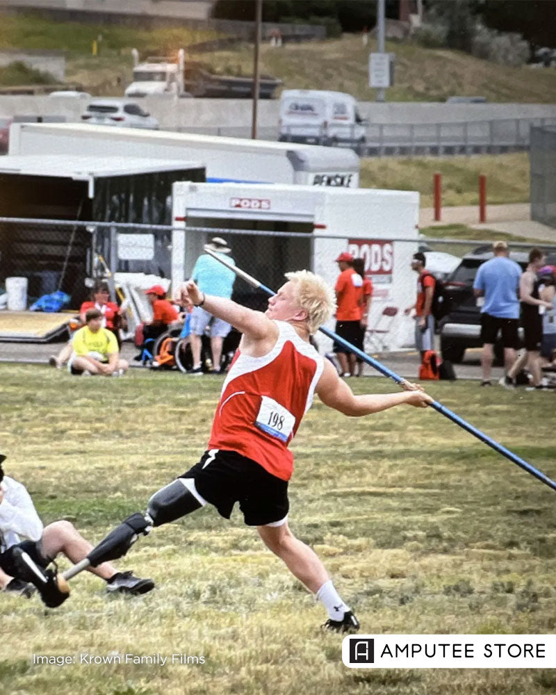 Amputee athlete with a prosthetic leg competing in a javelin throw during an adaptive sports event.