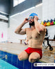 Bilateral above-knee amputee preparing for aquatic exercise at an indoor swimming pool.