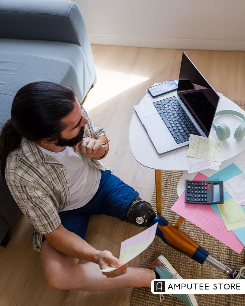 Man with prosthetic leg reviewing bills and documents at home, representing prosthetic tax deductions and financial planning.