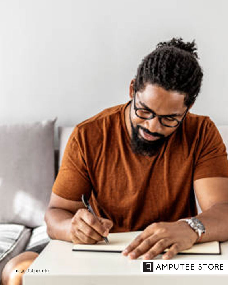 Man journaling in a bright living room, symbolizing self-care, mindfulness, and daily joy strategies. 