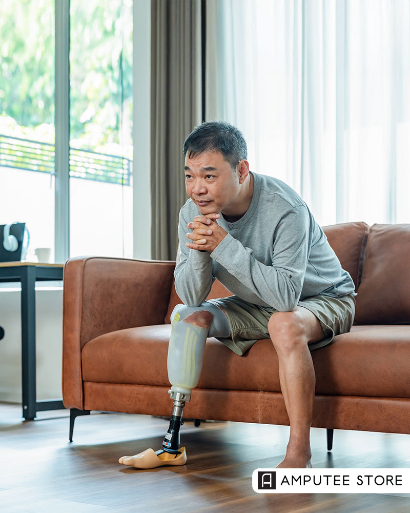 Man with a lower-limb prosthetic leg sitting thoughtfully on a couch, reflecting on loneliness, mental health, and finding connection during challenging life transitions after amputation.