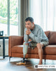Man with a lower-limb prosthetic leg sitting thoughtfully on a couch, reflecting on loneliness, mental health, and finding connection during challenging life transitions after amputation.