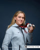 Ali Truwit, a Paralympian in a Team USA hoodie, smiles while holding two silver medals.