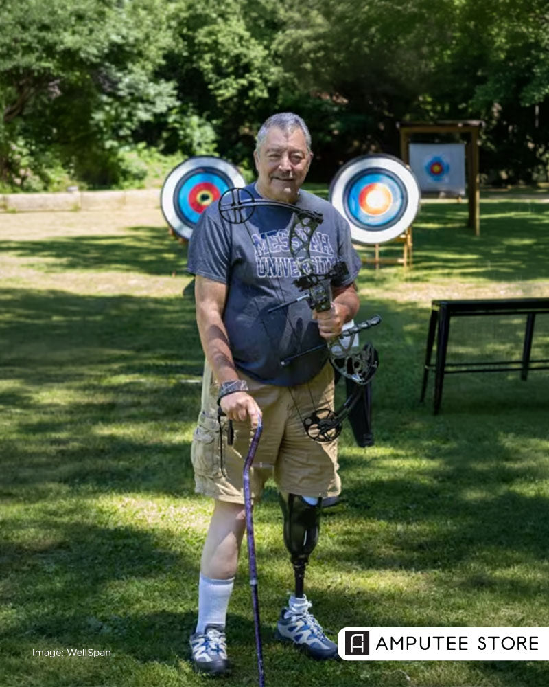 Bob Aims, a below-knee amputee, holds a compound bow at an outdoor archery range, highlighting the benefits of adaptive archery and peer support after limb loss.