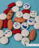 Colorful pills and tablets with hand-drawn happy and sad faces on a blue background, representing the myths and realities surrounding antidepressants.