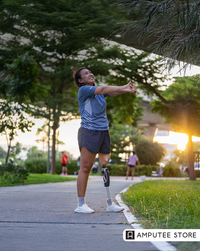 Amputee woman warming up for a morning run in the park, wearing a prosthetic leg and athletic gear, symbolizing motivation and progress toward goals.