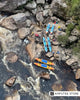 An aerial view of a rocky riverbank with rafts and rescue personnel gathered near turbulent rapids. 
