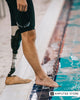 Person with a prosthetic leg standing by a swimming pool for an article about waterproof prosthetic legs, shower-safe prostheses, swim legs, and water-safe prosthetic options.